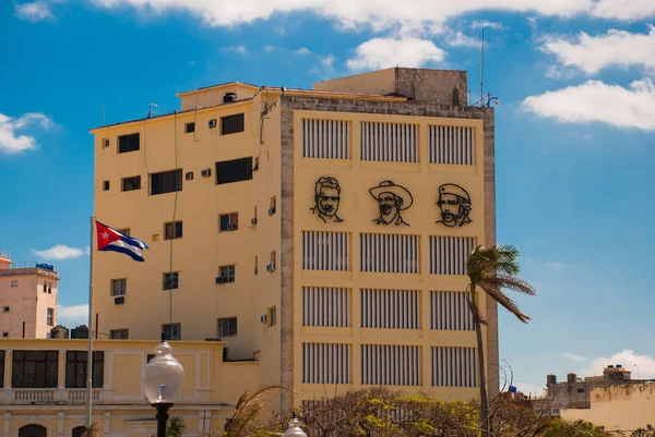 Drie portretten zijn op de muur van het gebouw: Che Guevara, Fidel Castro. De Cubaanse vlag ontwikkelt. Cuba. Havana — Stockfoto