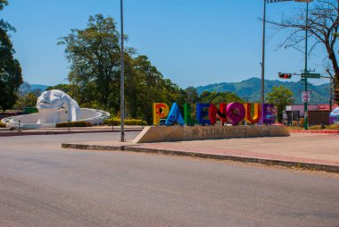 Palenque, Chiapas, Meksika. Şehir, Palenque tarafından büyük renkli harflerle yazılmış adı. Sokakta beyaz başlı heykel.