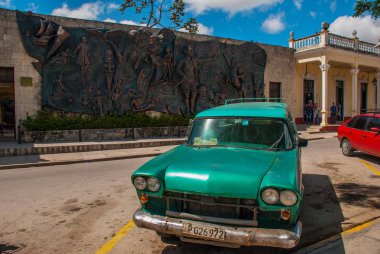 Holguin, Küba: Şehir merkezinde duvardaki büyük tarihsel rahatlama. Eski retro otomobil park