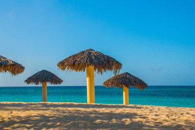 Turkuaz mavi su arka plan üzerinde plaj şemsiye vardır. Playa Esmeralda, Holguin, Küba