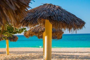 Turkuaz mavi su arka plan üzerinde plaj şemsiye vardır. Playa Esmeralda, Holguin, Küba