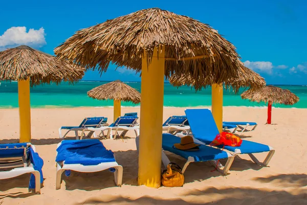 Μπλε ξαπλώστρες με ομπρέλες στην παραλία. Στο φόντο των στα γαλαζοπράσινα νερά της Καραϊβικής. Playa Esmeralda, Holguin, Κούβα — Φωτογραφία Αρχείου