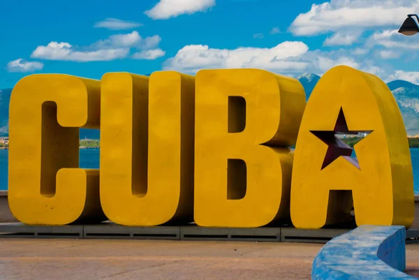 La inscripción de la CUBA. Enormes letras en el paseo marítimo, contra un cielo azul con nubes en Santiago de Cuba . — Foto de Stock