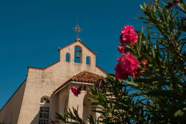 Červené květy v pozadí katolické církve ve vesnici poblíž města Cienfuegos, Kuba. — Stock fotografie