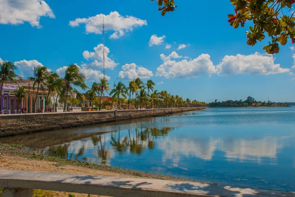 Cienfuegos, Kuba: Promenade i staden, coconut palm träd reflekteras i vattnet. Solig dag med blå himmel och moln — Stockfoto