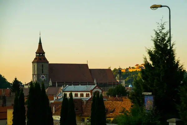 BRASOV, RUMANIA: Iglesia negra con un fondo de cielo azul con nubes en Brasov . — Foto de Stock