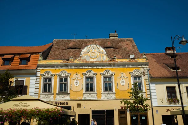 SIBIU, ROMÉNIA: A chamada casa com olhos, telhados no telhado. Casas multicoloridas tradicionais na rua com janelas Dormer incomuns nos telhados das casas — Fotografia de Stock