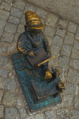Wroclaw, Polonya: Cüce oturuyor ve bir kitap okuyor, şapka heykeli olan ünlü bronz minyatür cüce
