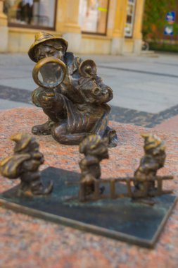 Wroclaw, Polonya: Büyüteçle fotoğrafçı kız merdiven taşıyan cücelere bakıyor.
