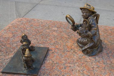 Wroclaw, Polonya: Büyüteçle fotoğrafçı kız merdiven taşıyan cücelere bakıyor.