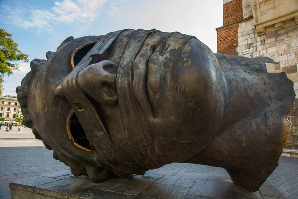 Krakau, Polen: Eros Bendato reusachtig hoofdbeeld in Rynek Glowny, Krakau. De bronzen noggin werd in 1999 door Igor Mitoraj gebeeldhouwd en verhuisde in 2003 naar Krakau.. — Stockfoto