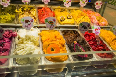 Dükkandaki tezgahın üzerinde farklı aromalı renkli dondurma. Krakow, Polonya