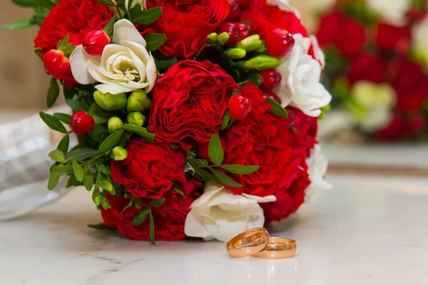 Día de San Valentín. Anillos de boda y un hermoso ramo de flores rojas y blancas . — Foto de Stock