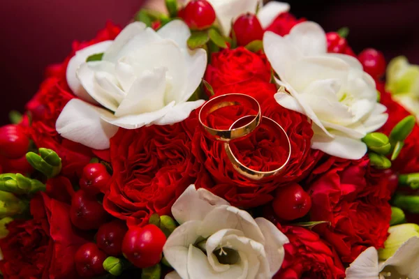 Valentinstag. Hochzeit. Trauringe und ein schöner Strauß roter und weißer Blumen. — Stockfoto