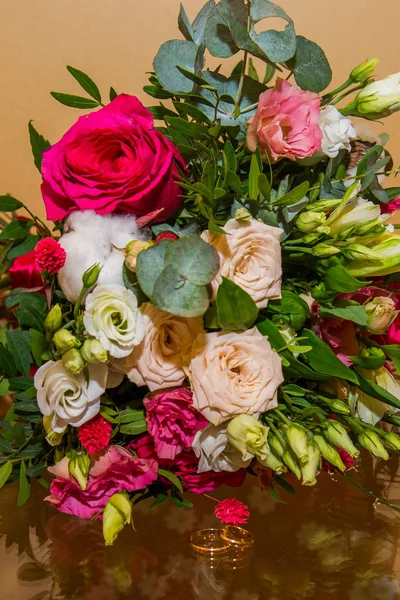 BODAS, Anillos y flores: Anillos de novia y ramo de rosas rojas y hermosas flores blancas — Foto de Stock