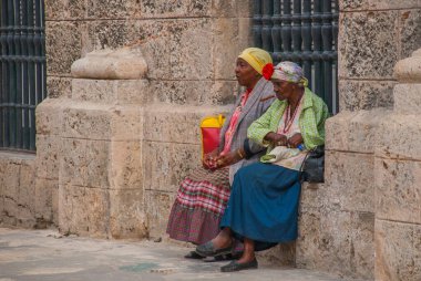 Havana, Küba - Mart 2018: Ulusal kıyafetler giymiş iki kadın oturup turistlerin fotoğraflarını bekliyor
