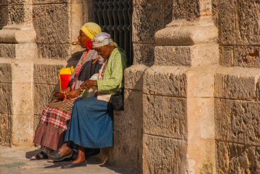 Havana, Küba - Mart 2018: Ulusal kıyafetler giymiş iki kadın oturup turistlerin fotoğraflarını bekliyor