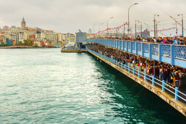 İnsanlar bulutlu bir havada Galata Köprüsü 'nden balık avlıyor. Uzak Galata kulesinde ve evde. İstanbul, dünyada iki kıtada yer alan tek metropol..