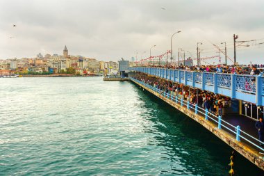 İnsanlar bulutlu bir havada Galata Köprüsü 'nden balık avlıyor. Uzak Galata kulesinde ve evde. İstanbul, dünyada iki kıtada yer alan tek metropol..