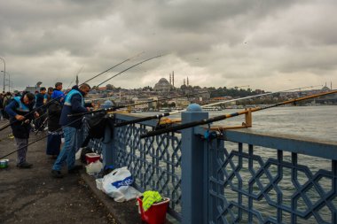 İSTANBUL, TURKEY - Ekim 2018: Bulutlu havada Galata Köprüsü 'nden balık tutan insanlar.