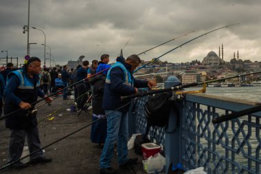 İSTANBUL, TURKEY - Ekim 2018: Bulutlu havada Galata Köprüsü 'nden balık tutan insanlar.
