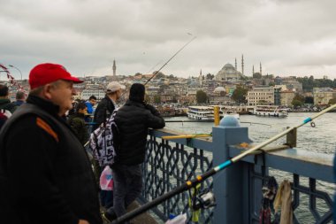 İSTANBUL, TURKEY - Ekim 2018: Bulutlu havada Galata Köprüsü 'nden balık tutan insanlar.