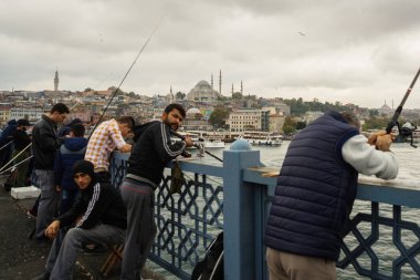 İSTANBUL, TURKEY - Ekim 2018: Bulutlu havada Galata Köprüsü 'nden balık tutan insanlar.