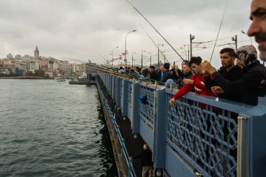 İSTANBUL, TURKEY - Ekim 2018: Bulutlu havada Galata Köprüsü 'nden balık tutan insanlar.