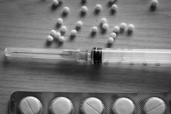 Şırınga ve tabletler tahta yüzeyde yer almaktadır..