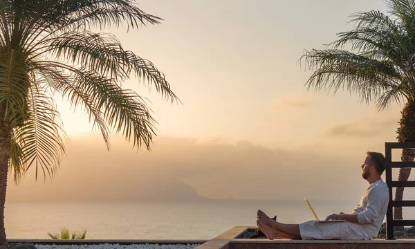 Gün batımında dizüstü bilgisayar ile genç adam