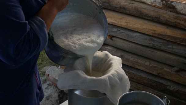 Una mujer vierte leche en una lata a través de una gasa — Vídeo de stock