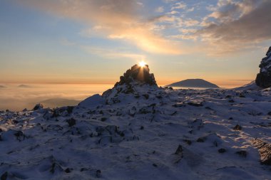 Hiking kış: Güneş dağlarda bir kaya üzerinde akşam güzel gökyüzü altında iletiye göz atar