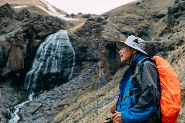 Ledande asiatiska hiker nära vattenfallet — Stockfoto