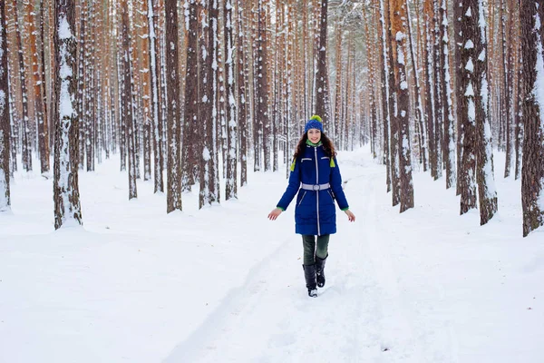 Ung kvinna njuter av vintern i snöig park — Stockfoto