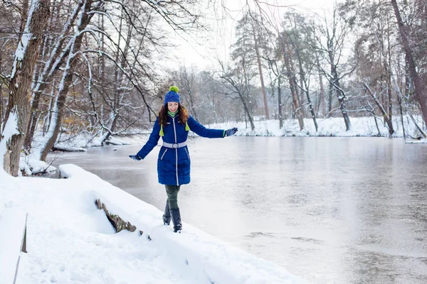 Ung kvinna njuter av vintern i snöig park — Stockfoto