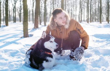 Sibirya husky köpek karlı Park ile oynarken adam