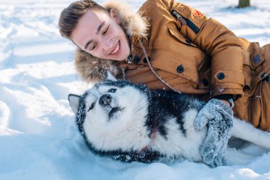 Sibirya husky köpek karlı Park ile oynarken adam