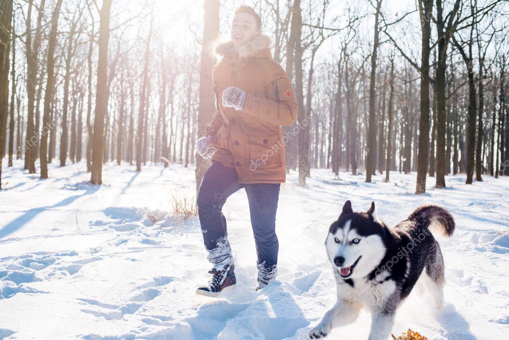 man playing with siberian husky dog in snowy park
