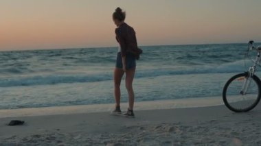 Gün batımı veya gündoğumu sırasında kumsalda yürüyen genç güzel kadın