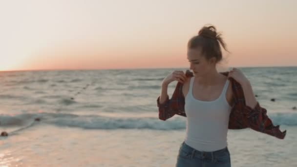 夕日や日の出の中にビーチを歩く若い美しい女性 — ストック動画