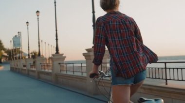 genç kadın binicilik bisiklet sahilde sunset bulvarında gündoğumu sırasında oldukça
