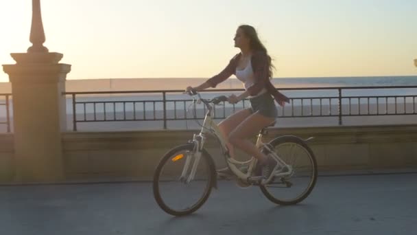 若いきれいな日の出の日没時にビーチで女性乗馬自転車 — ストック動画