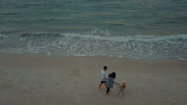 husky köpek ile sahilde yürüyen genç mutlu çiftin havadan görünümü