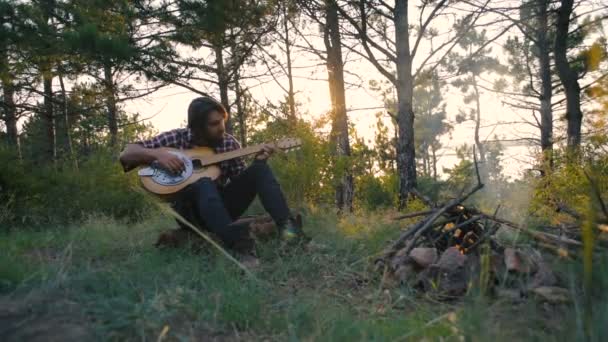 Cântând Chitară Stând Lângă Focul Tabără Pădure Timpul Apusului Soare — Videoclip de stoc