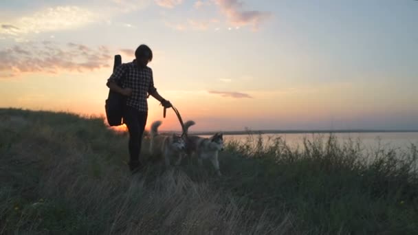 Homem Com Guitarra Andando Com Dois Cães Husky Siberianos Perto — Vídeo de Stock