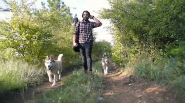 adam gitar ormandaki iki Sibirya husky köpek ile yürüme ile