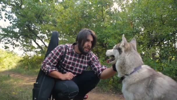 Hombre Con Guitarra Jugando Con Dos Perros Husky Siberianos Bosque — Vídeos de Stock