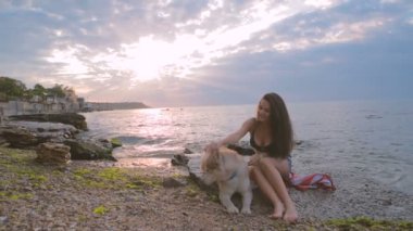 Husky köpekle oynamayı sahilde günbatımı veya gündoğumu sırasında genç güzel kadın