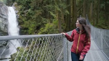 Şelalenin yakınındaki asma köprü üzerinde yürüyen kadın