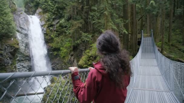 Frau Läuft Auf Hängebrücke Der Nähe Des Wasserfalls — Stockvideo